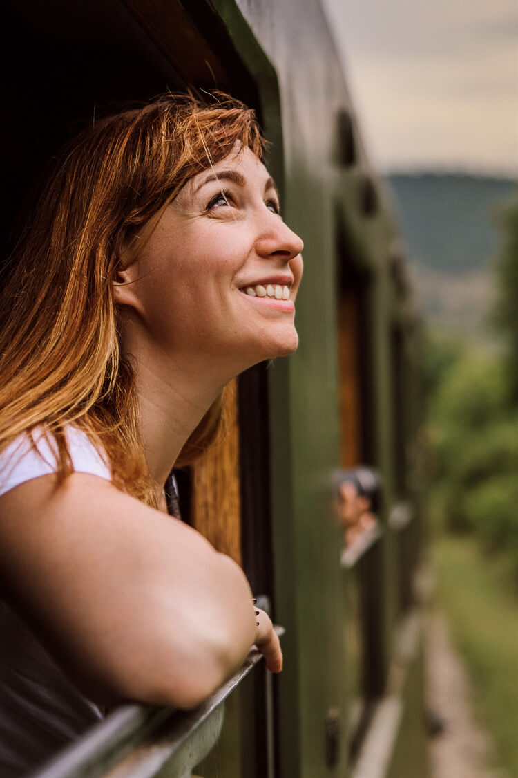 Woman looking out a train window at the greenery